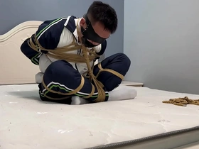Asian boy in Ebi-position bondage with blindfold and tapegag for an erotic experience.